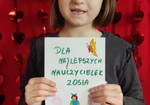 Dziewczynka na tle serduszek z kartką dla cioć.
