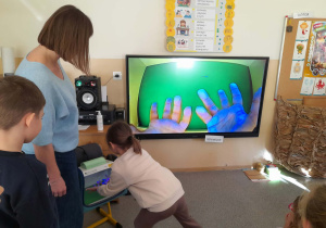 Pani z sanepidu pokazuje obraz umytej dłoni jednej z dziewczynek.