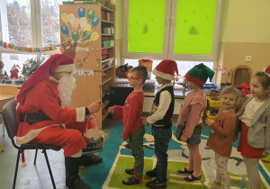 Dzieci otrzymują upominek od Mikołaja.