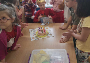 Dzieci biją brawo dla Mikołaja za zdmuchnięcie świeczek.