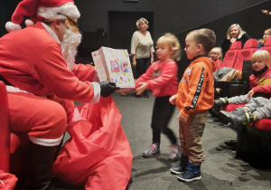 Dzieci odbierają prezent od Mikołaja.