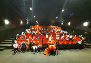 Grupowe zdjęcie z Mikołajem w sali kinowej.