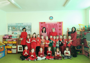 Zdjęcie grupowe w czerwonych ubraniach z serduszkami w ręku.