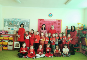 Zdjęcie grupowe w czerwonych ubraniach z serduszkami w ręku.