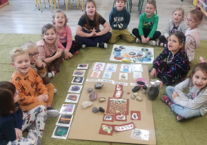 Dzieci siedzą na dywanie i biorą udział w zajęciach o planetach.