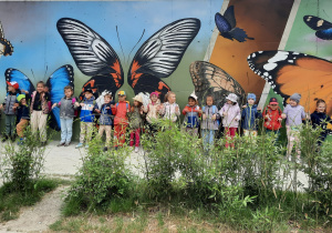 Zdjęcie grupowe na tle motyli malowanych na ścianie.