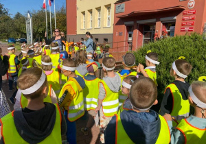 Dzieci idą korowodem w odblaskowych kamizelkach do Urzędu Miasta.