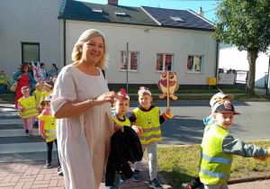 Dzieci maszerują ulicami miasta świętując dzień przedszkolaka.