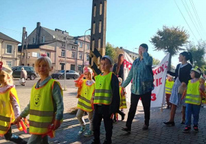 Dzieci maszerują ulicami miasta świętując dzień przedszkolaka.