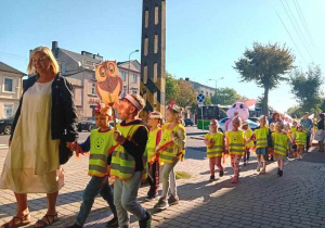 Dzieci maszerują ulicami miasta świętując dzień przedszkolaka.