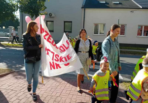 Dzieci maszerują ulicami miasta świętując dzień przedszkolaka.