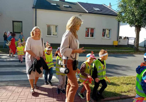 Dzieci maszerują ulicami miasta świętując dzień przedszkolaka.