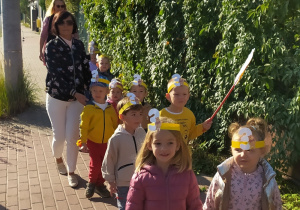 Dzieci maszerują ulicami miasta świętując dzień przedszkolaka.