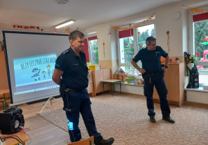 Policjanci na tle telebimu z bajką.