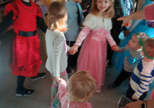 Dzieci przebrane za postacie z bajek bawią się na balu karnawałowym.