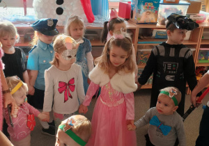 Dzieci przebrane za postacie z bajek bawią się na balu karnawałowym.