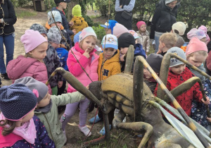 Dzieci oglądają figurę owada na ścieżce edukacyjnej.