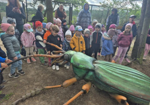 Dzieci oglądają figurę owada na ścieżce edukacyjnej.