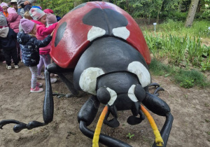 Dzieci oglądają figurę owada na ścieżce edukacyjnej.