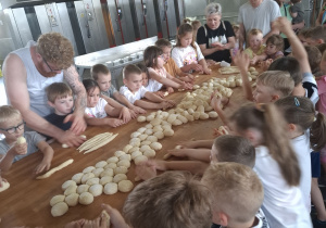 Dzieci przy dużym stole robią własne wypieki.