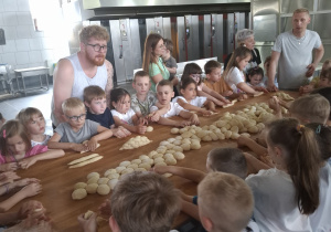 Dzieci przy dużym stole robią własne wypieki.