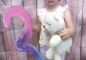 Jubilatka w czapeczce trzyma cyfrę 3.