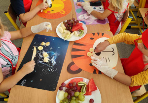 Dzieci kroją owoce na małe części.