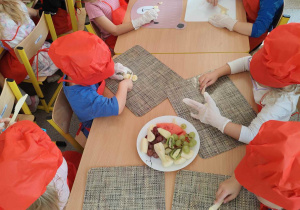 Dzieci kroją owoce na małe części.