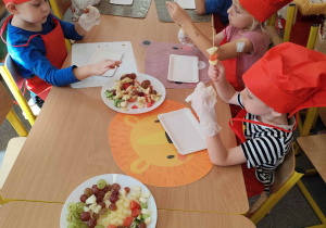 Dzieci kroją owoce na małe części.