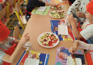 Dzieci kroją owoce na małe części.