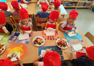 Dzieci kroją owoce na małe części.