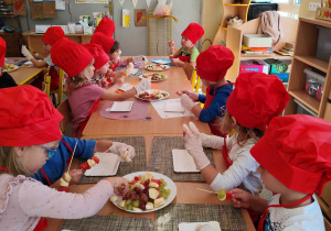 Dzieci kroją owoce na małe części.