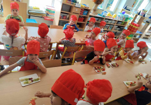 Dzieci jedzą owocowe szaszłyki.