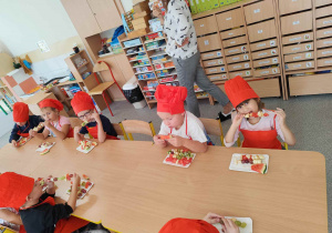 Dzieci jedzą owocowe szaszłyki.