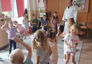 Sportowiec pokazuje dzieciom ćwiczenia karate.