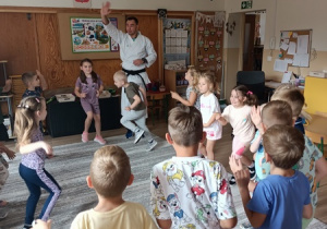Sportowiec pokazuje dzieciom ćwiczenia karate.