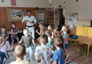 Sportowiec pokazuje dzieciom ćwiczenia karate.