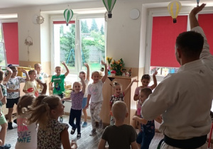 Sportowiec pokazuje dzieciom ćwiczenia karate.