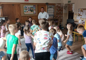 Sportowiec pokazuje dzieciom ćwiczenia karate.