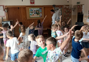 Sportowiec pokazuje dzieciom ćwiczenia karate.