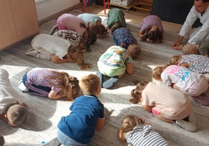 Sportowiec pokazuje dzieciom ćwiczenia karate.