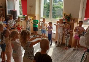 Sportowiec pokazuje dzieciom ćwiczenia karate.