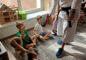 Sportowiec pokazuje dzieciom ćwiczenia karate.