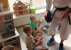 Sportowiec pokazuje dzieciom ćwiczenia karate.