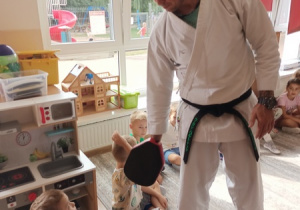 Sportowiec pokazuje dzieciom ćwiczenia karate.