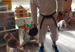 Sportowiec pokazuje dzieciom ćwiczenia karate.