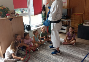 Sportowiec pokazuje dzieciom ćwiczenia karate.