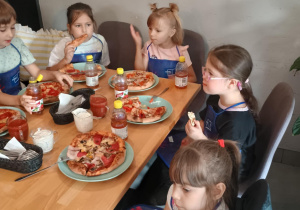 Dzieci konsumują pizzę.