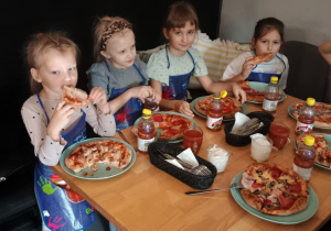 Dzieci konsumują pizzę.