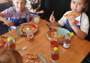 Dzieci konsumują pizzę.